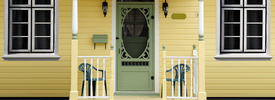 A green screen door on a yellow house