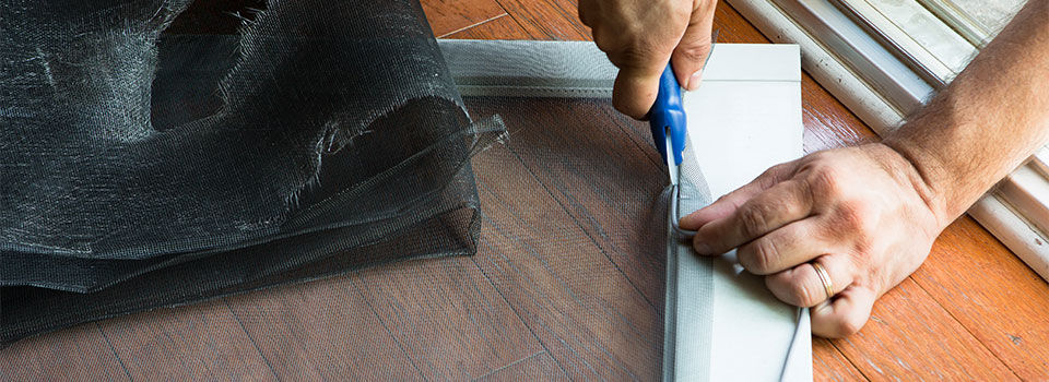 A close up image of a person replacing a window screen using a screen repair tool 