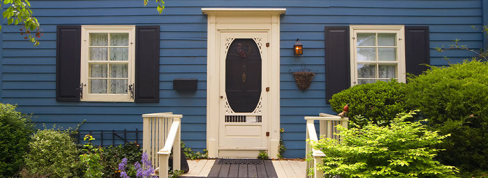 Two-story Traditional North American style residential houses with deep blue exteriors situated on a mature street with well-manicured landscaping.