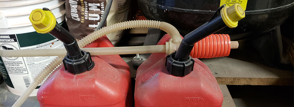 A siphon pump laying across to gas cans