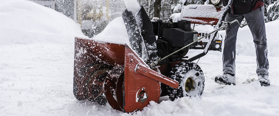 Man pushing a snowblower clearing driveway