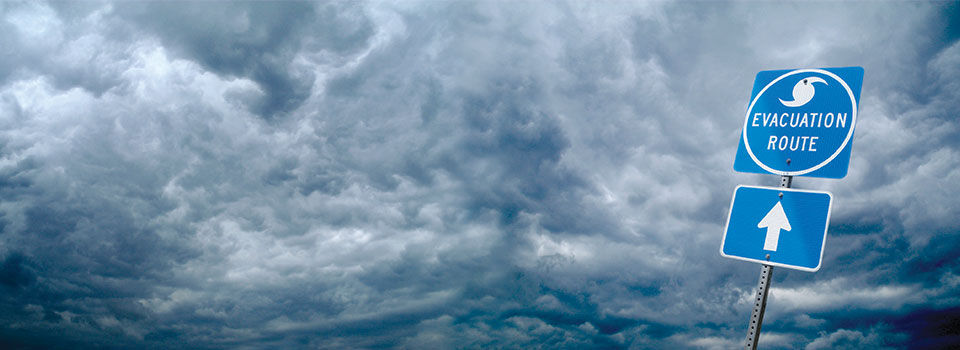 Dark cloudy skies behind a blue evacuation route sign