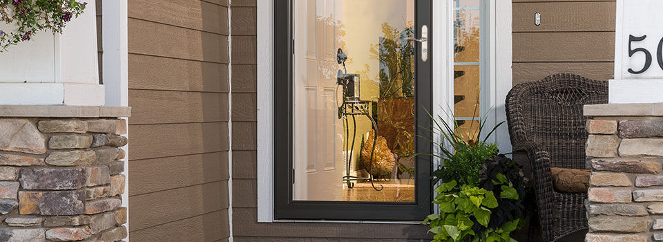 A close up image of a modern house front door with black storm door attached 