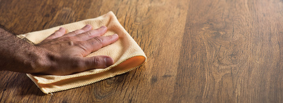 Person using an orange microfiber cloth to wipe down wood floor