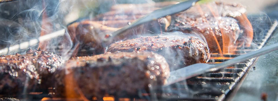 Flipping burgers on a grill with tongs