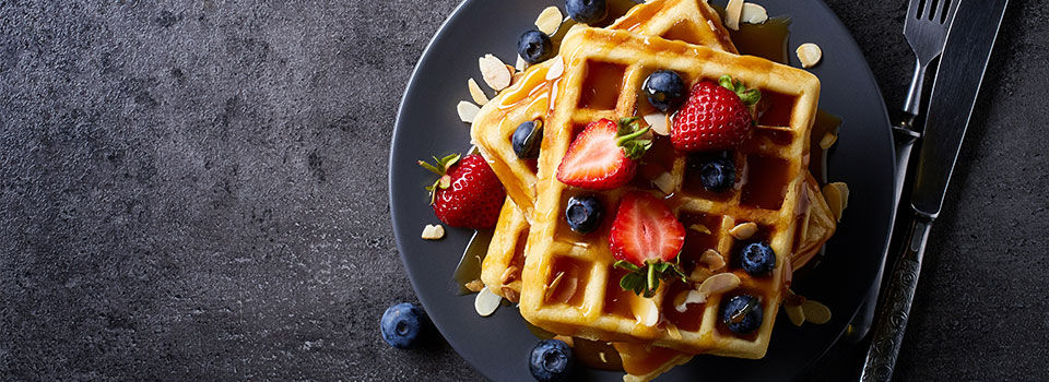 Overhead shot of a plate of waffles with berries and syrup drizzled on top