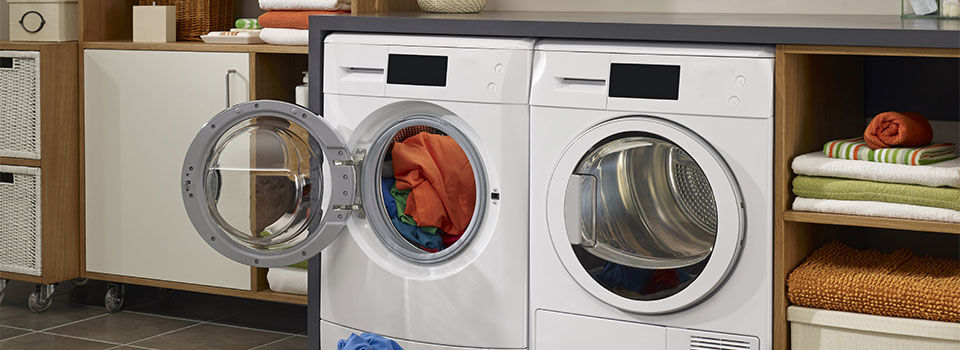 A washer and dryer door open with a basket of clean clothes in laundry room