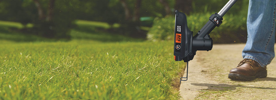 Person edging their lawn next to the sidewalk, close-up