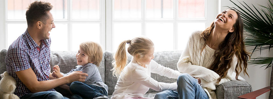 Little kids tickling parents family having fun sitting on couch