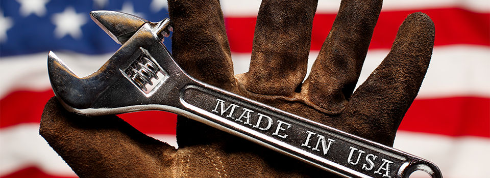 Made in USA steel wrench in the hand of a hard working American with an American flag in the background