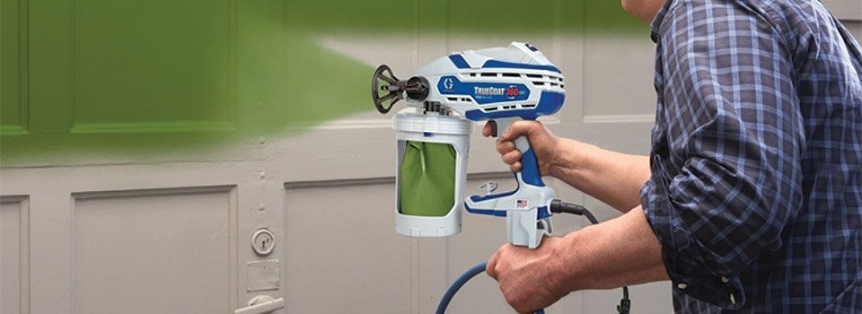 A person using a paint sprayer to paint walls green