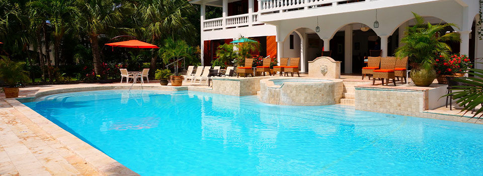 Relaxing poolside view of a terrace with red umbrellas and modern patio furniture on a sunny day.