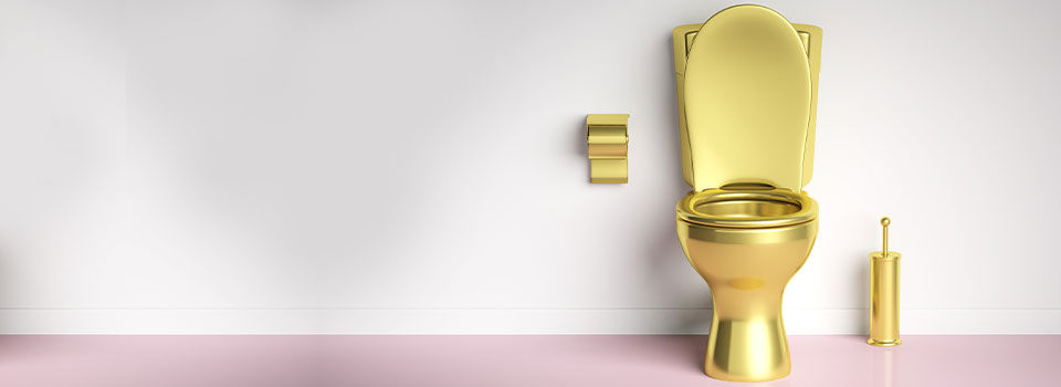 A golden toilet on a pink and white background