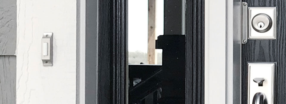 A close up image of a silver door bell in front of a black door 