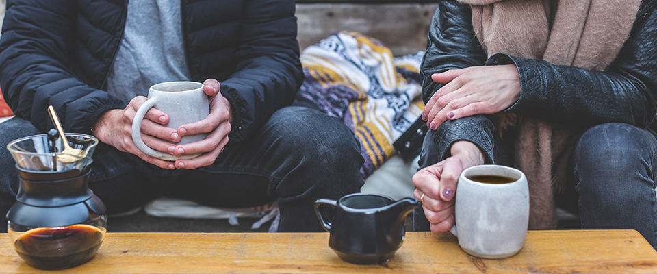 Photo of a romantic couple having a warm drink while sitting on the terrace of their loft apartment on a cold winter day