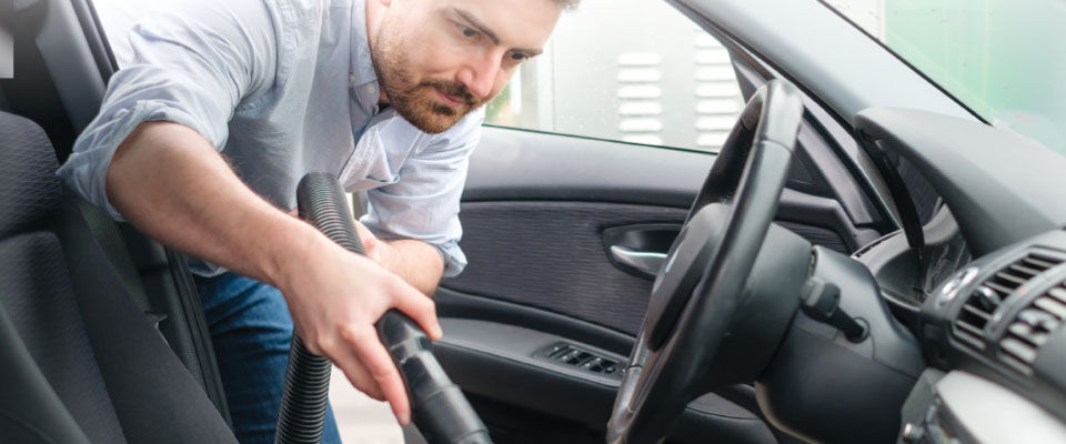 Man using a wet/dry vac to clean car