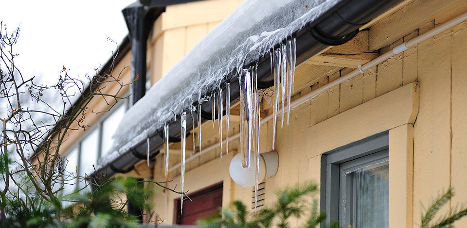 Icicles hanging off the gutters of a yellow house