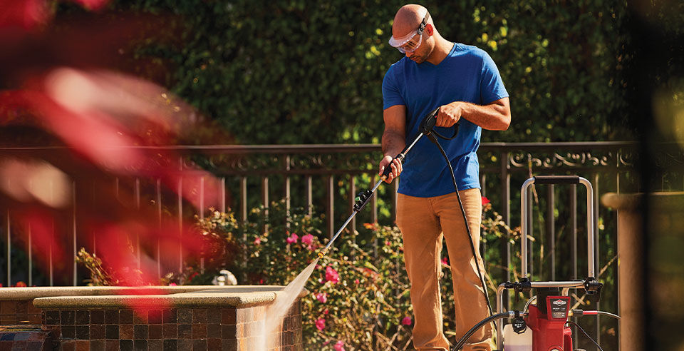 Man power washing bricks while wearing eye protection