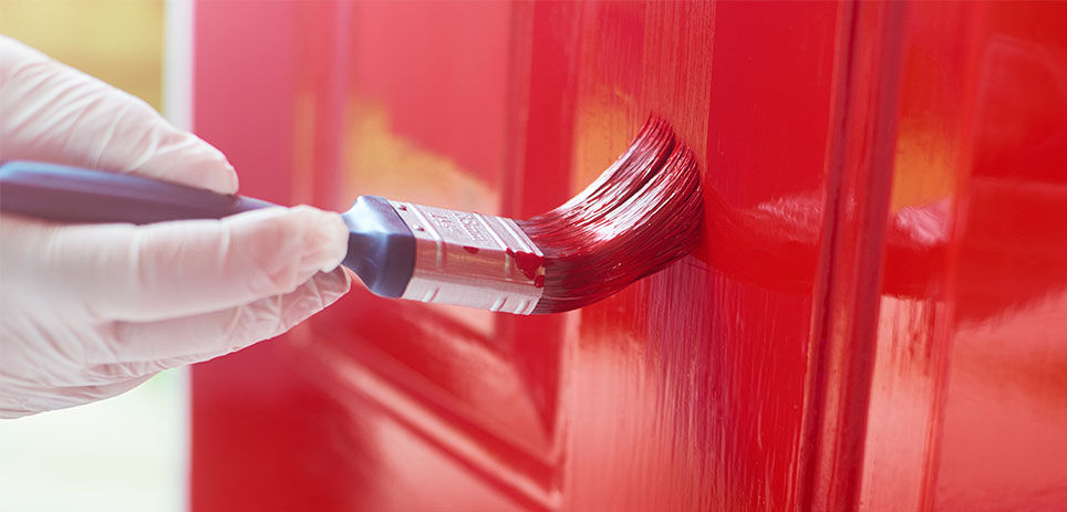 Homeowner applies a fresh coat of paint to his front door, instantly transforming the look of his home. The vibrant color pops against the neutral exterior, making a statement that is both stylish and inviting.