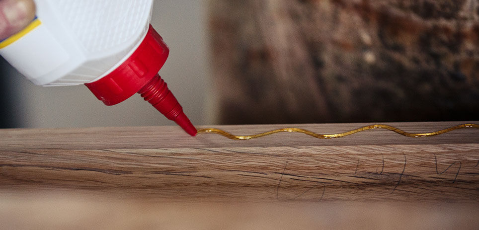 Squeezing wood glue out of a bottle and on to a strip of wood