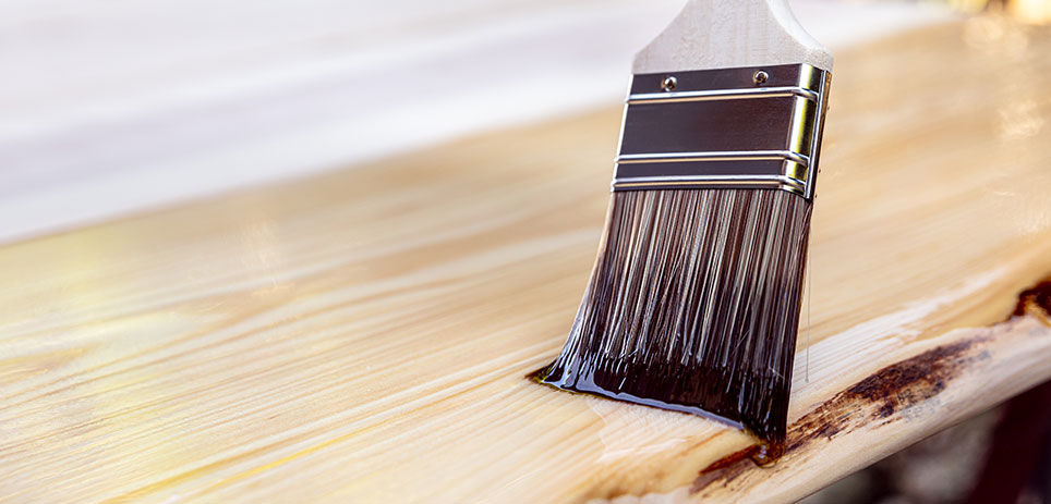 Person using a paint brush to apply a pre-stain