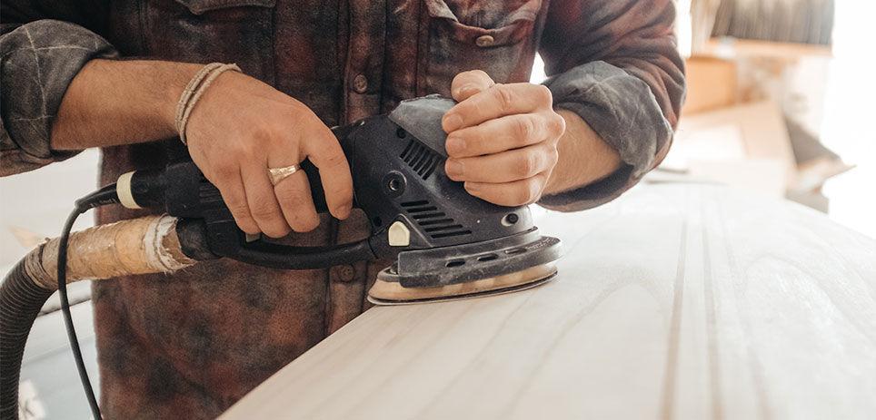 Person sanding down a piece of wood to be as smooth as possible