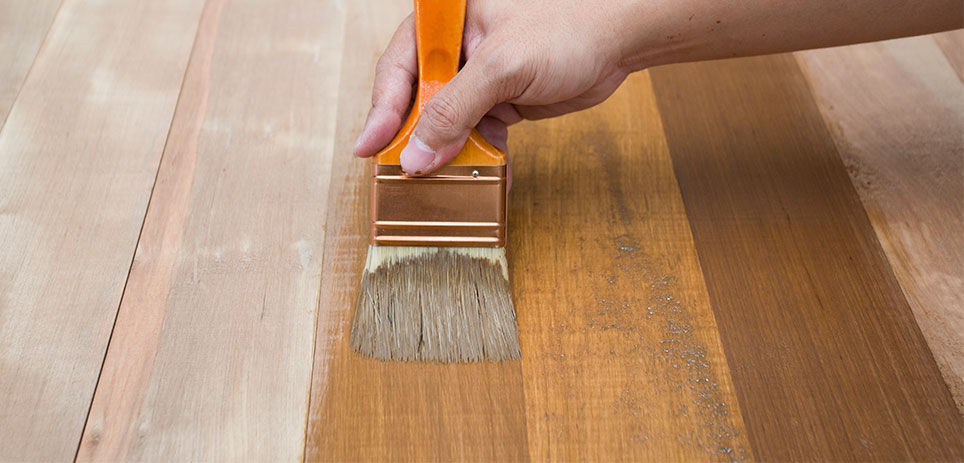 Person applying the wood stain with a paint brush