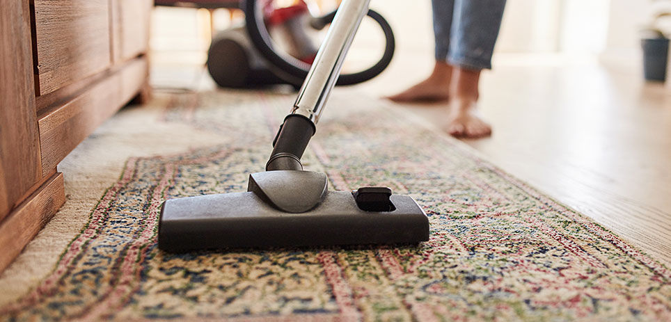 Woman vacuuming rug, close-up