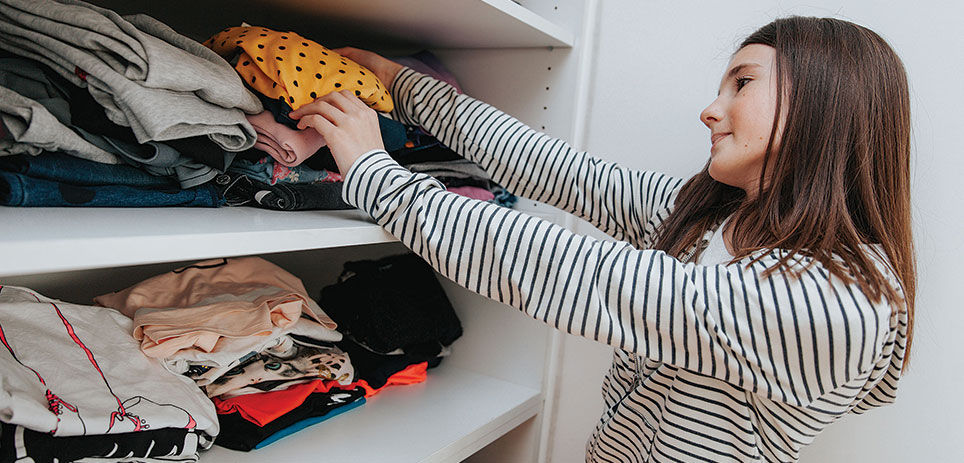 Woman putting away folded clothes in her closet