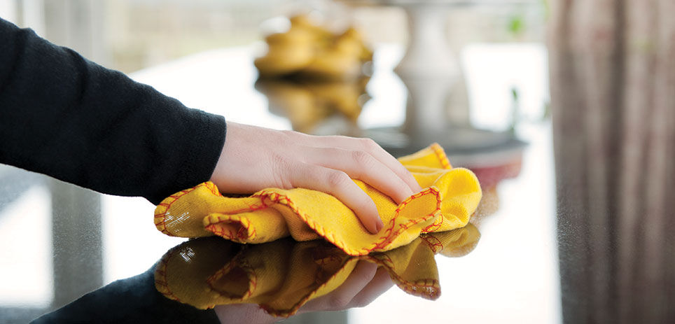 Person using an orange microfiber cloth to wipe down kitchen countertop