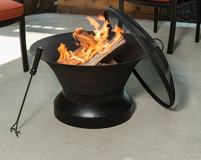 Outdoor patio with a wood-burning black metal fireplace, featuring a poker stick and surrounded by winter patio furniture and accessories for creating a cozy and inviting atmosphere during outdoor winter gatherings. Perfect for adding warmth and ambiance to your winter patio entertainment.