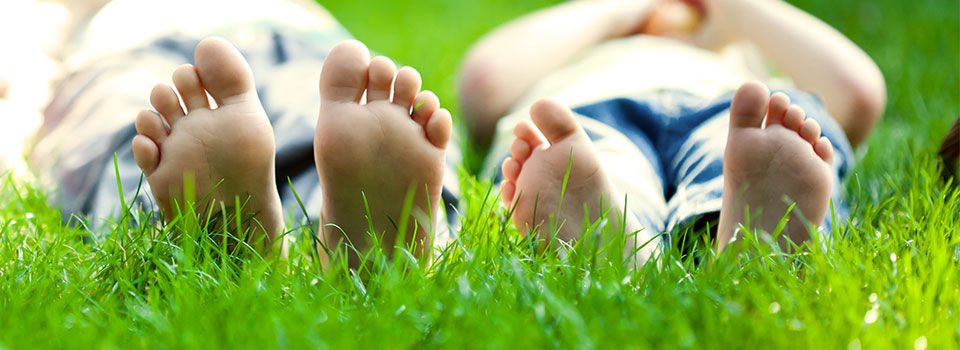 Two people laying in the grass with their bare feet