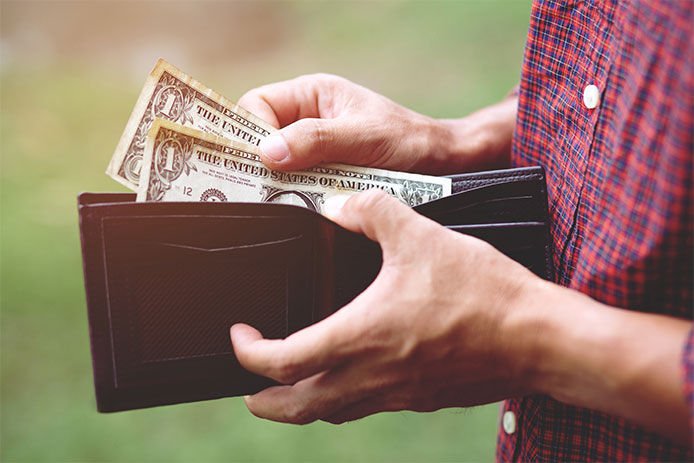 Person pulling dollar bills from their wallet