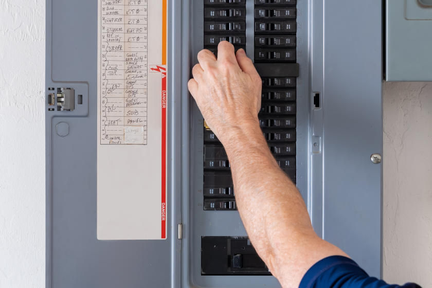 Man's hand turning off circuit breaker in home electrical box